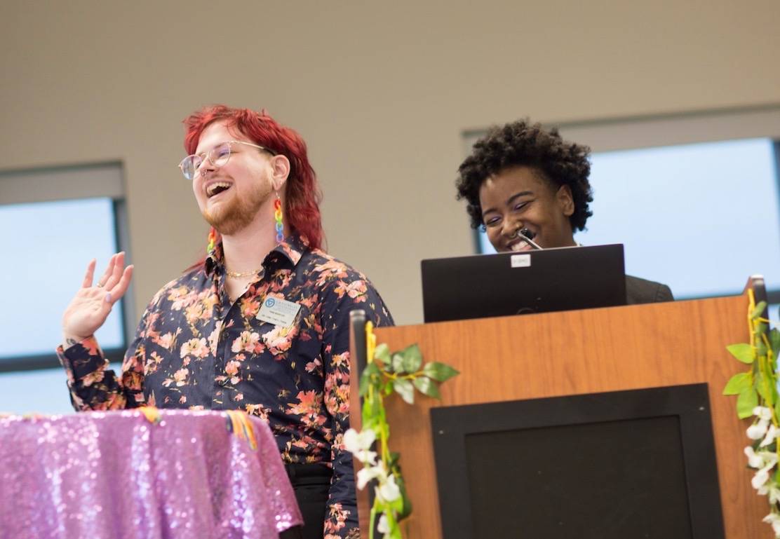Two people stand behind a podium during Lavender Graduation